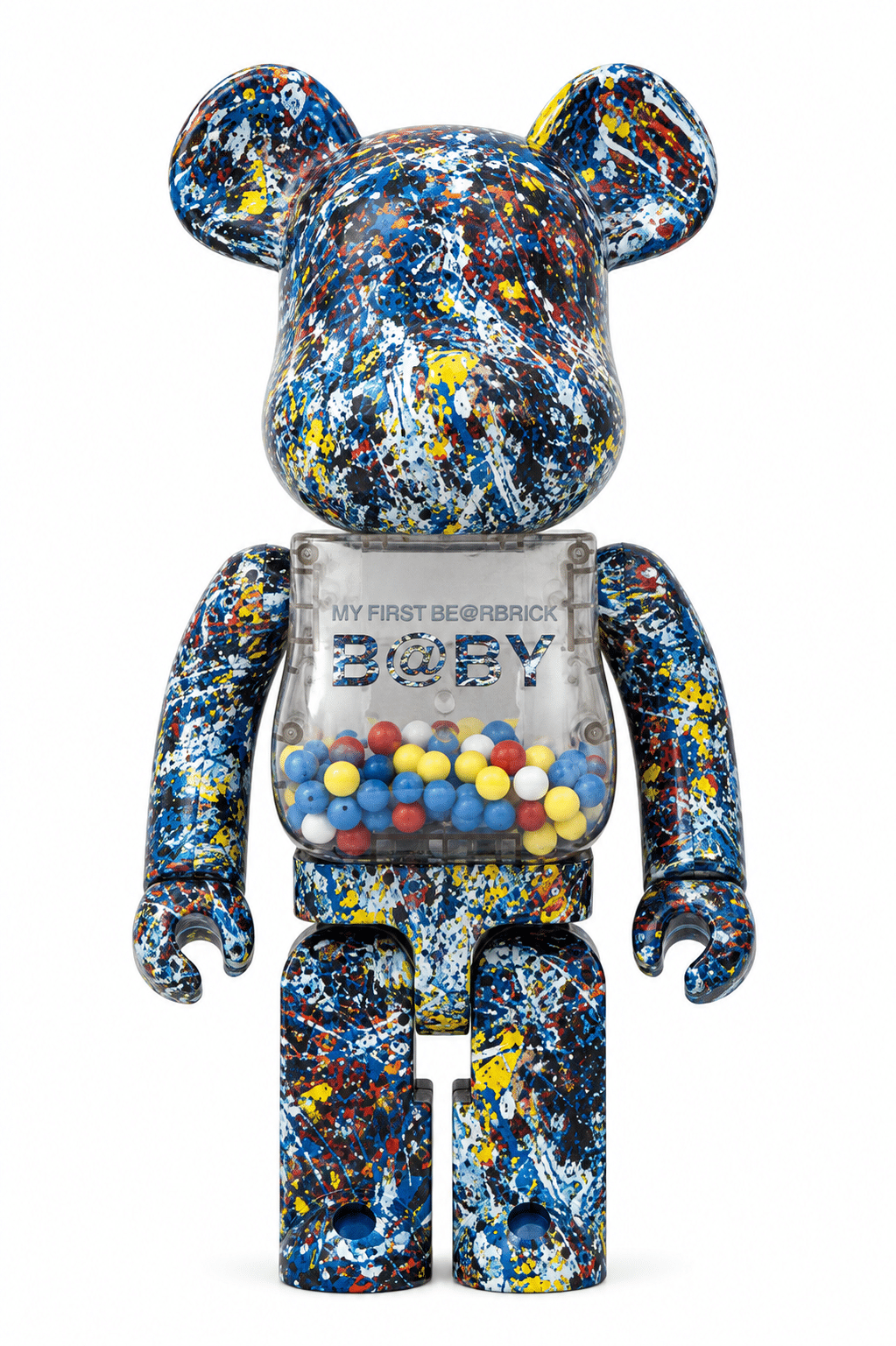 A Bearbrick figure covered in blue, yellow, red, and white paint splatters, with a clear torso showing "MY FIRST BE@RBRICK B@BY" and colorful beads.