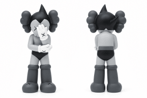 Two KAWS "Astro Boy" figures in grayscale, one facing forward covering its face, the other facing backward.