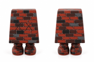 Two brick-patterned figures with small, round feet stand on a white surface; the left figure has black "XX" marks.