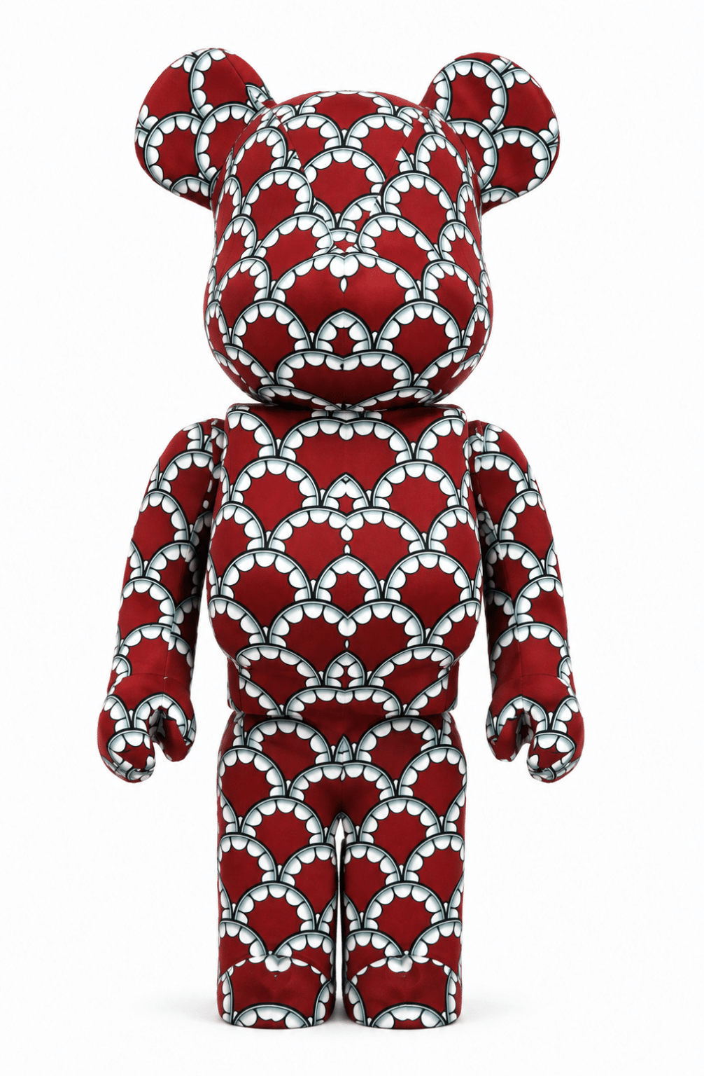 A red Bearbrick toy covered in a repeating pattern of white and black scalloped shapes on a white background.
