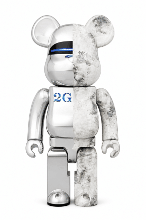 A Bearbrick figure is split vertically, half shiny chrome with "2G" on its chest, and half white marble.