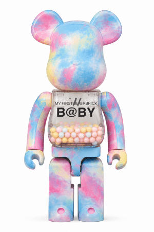 A tie-dye pink, blue, and yellow Bearbrick toy with a clear chest full of pastel balls and "B@BY" text.