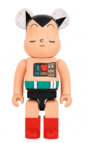 A beige Astro Boy Bearbrick figure with closed eyes, black hair, and clear ears, revealing a red heart in its chest.