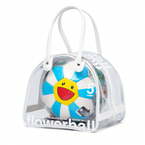 A clear plastic handbag with white trim holds a blue and white soccer ball featuring a yellow smiling flower face.