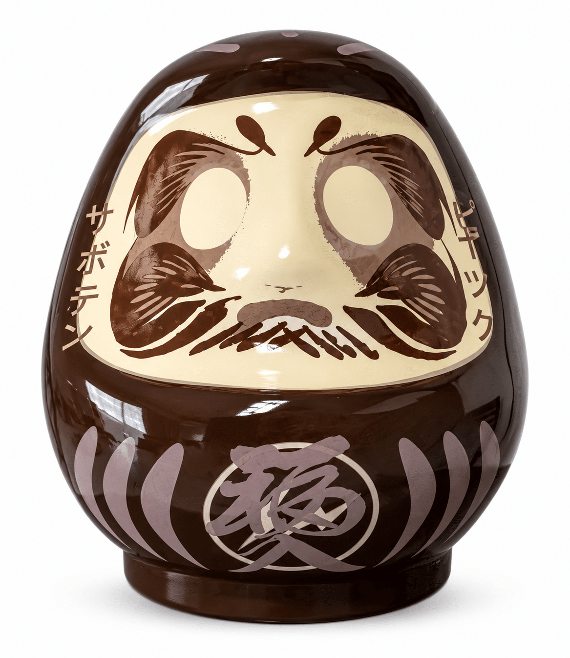 A brown Daruma doll has a cream-colored face with dark brown facial features and Japanese text "サボテン" and "プティック" on its sides.
