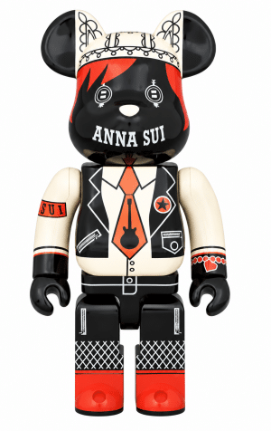 A black and white Bearbrick figure with red accents, "ANNA SUI" on its chest, and a guitar on its tie.