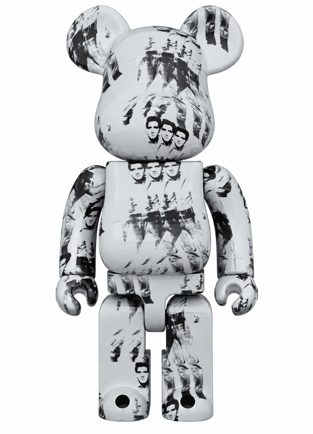 A white Bearbrick toy with black and white images of Elvis Presley from Andy Warhol's "Triple Elvis" artwork.