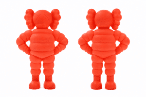 Two orange KAWS Companion figures stand side-by-side, one facing forward with "XX" eyes, the other facing backward.