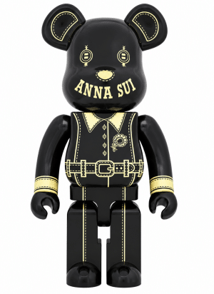 A black bear-shaped figurine with "ANNA SUI" on its face and gold outlines of a collared shirt and belt.